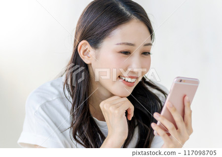 A woman watching a smartphone with a smile A woman watching a smartphone with a smile 117098705
