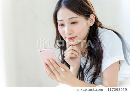 一位女士板著臉看著她的智慧型手機 117098959