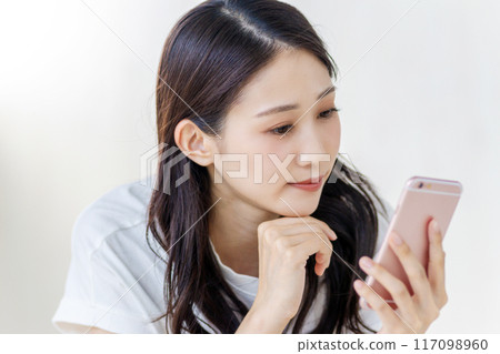 一位女士板著臉看著她的智慧型手機 117098960