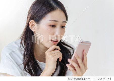 一位女士板著臉看著她的智慧型手機 117098961