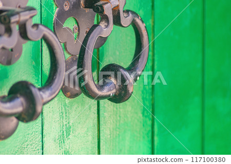 Iron forged handle bell on door with protruding part for easy hand grip to open or knock on door, thereby giving signal to open. Ancient devices, element of decoration created by forging metal 117100380