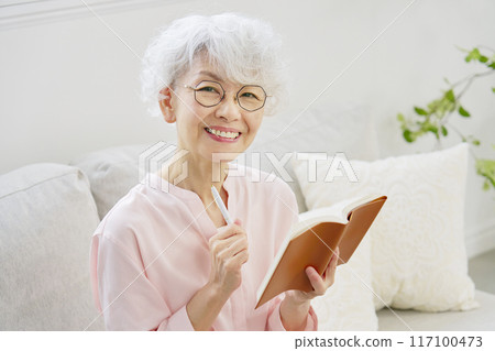 老婦人微笑著拿著行程表，看著相機 117100473