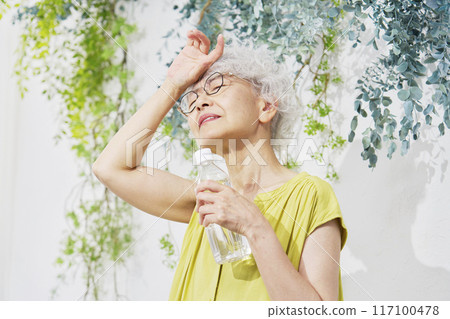 Senior woman holding a plastic bottle of water, looking at camera 117100478