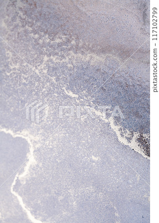 A close-up view of a natural, textured surface featuring a silver-white line winding through a lavender background 117102799