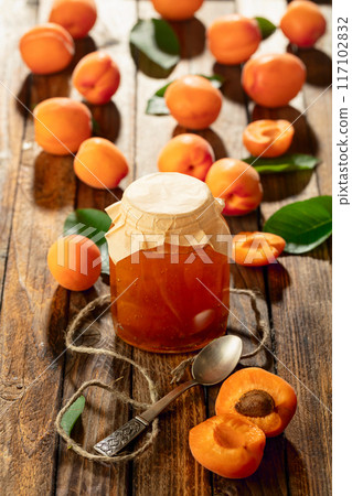 Apricot jam and fresh fruit on an old wooden table. 117102832