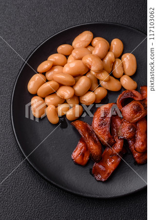 Fried sausages sliced with salt and spices as an ingredient for an English breakfast 117103062