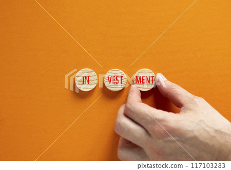 Investment symbol. Concept word Investment on beautiful wooden circles. Businessman hand. Beautiful orange background. Business investment concept. Copy space. Investment symbol. Concept word Investment on beautiful wooden circles. Businessman hand. Beautiful orange background. Business investment concept. Copy space. 117103283