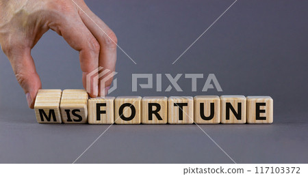 Fortune or misfortune symbol. Businessman turns wooden cubes and changes the concept word misfortune to fortune. Beautiful grey background, copy space. Business, fortune or misfortune concept. Fortune or misfortune symbol. Businessman turns wooden cubes and changes the concept word misfortune to fortune. Beautiful grey background, copy space. Business, fortune or misfortune concept. 117103372