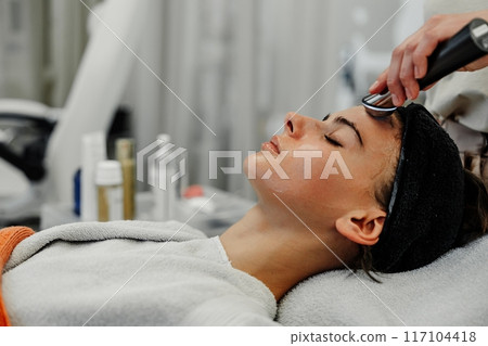 Young Woman Receiving Facial Treatment at Spa During Relaxing Afternoon Session 117104418