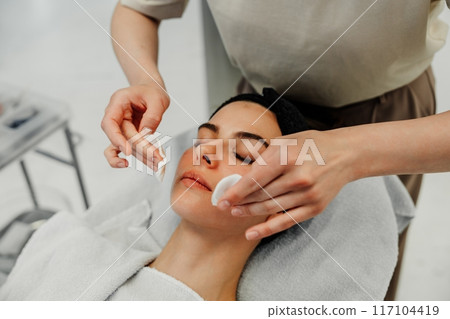 Woman Relaxing During Facial Treatment at Spa in Natural Light Setting 117104419