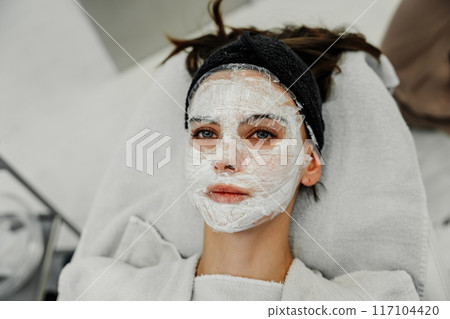 Young Woman Receiving Facial Treatment at Spa During Relaxing Afternoon 117104420