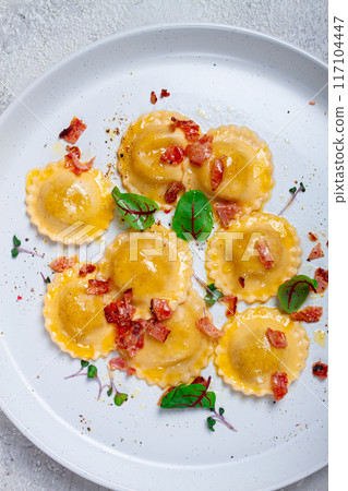 fresh ravioli, with butter, spices and herbs, fried bacon, on the table, top view, light background, no people, 117104447