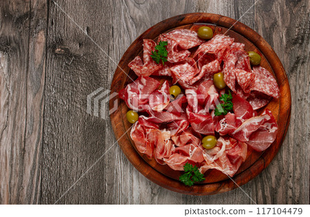 Assortment , sliced meat appetizer, prosciutto, salami and ham, with olives, on a wooden board, breakfast, top view, close-up, no people, 117104479