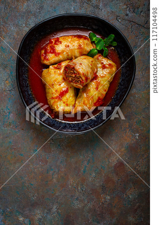 Stuffed cabbage rolls with minced meat, in tomato sauce, top view, without people, in the spotlight. 117104498