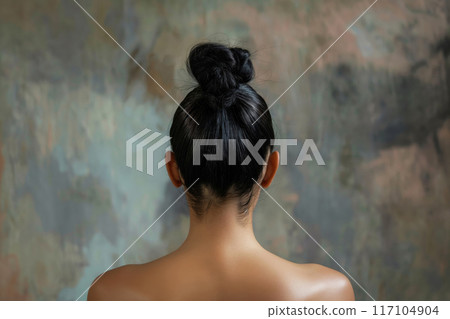 Rear view of a woman's top knot hairstyle against an artistic background 117104904