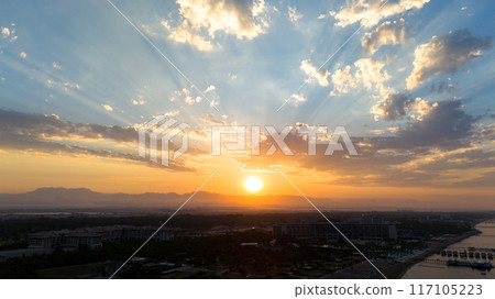 Dramatic sky illuminated by the rising sun over a beautiful sea coast Dramatic sky illuminated by the rising sun over a beautiful sea coast 117105223