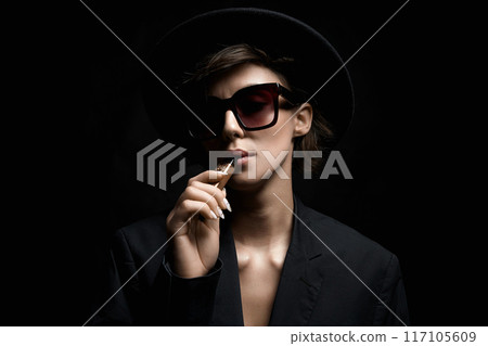 Beautiful woman in sunglasses and Hat Smoking electronic cigarette. smoking elegant  Lady 117105609