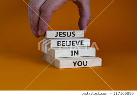 Jesus believe in you symbol. Concept words 'Jesus believe in you' on wooden blocks on a beautiful orange background. Businessman hand. Business, religion and Jesus believe in you concept. 117106896