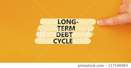 Long-term debt cycle symbol. Concept words Long-term debt cycle on wooden stick. Beautiful orange table orange background. Businessman hand. Business Long-term debt cycle concept. Copy space. 117106903