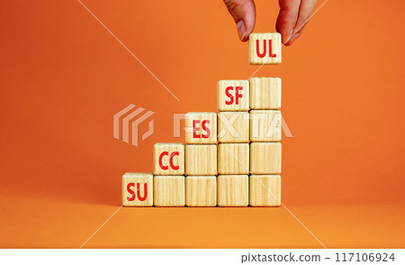 Successful symbol. Concept word Successful on beautiful wooden cubes. Beautiful orange background. Businessman hand. Business successful concept. Copy space. 117106924