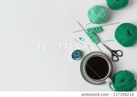 Composition of homemade needlework from cup of black coffee, scissors, mint ball for knitting and knitting needles, centimeter, pin. Hobbies of knitting warm clothes, toys, things for house. 117108218