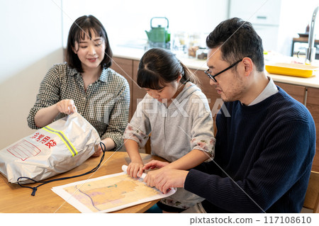 一家人小心翼翼地捲起危險地圖,準備放入緊急包中。 一家人小心翼翼地捲起危險地圖,準備放入緊急包中。 117108610