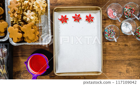 Flat lay. Creating snowflake-shaped cutout sugar cookies, dipped in chocolate, and adorned with different toppings. 117109042