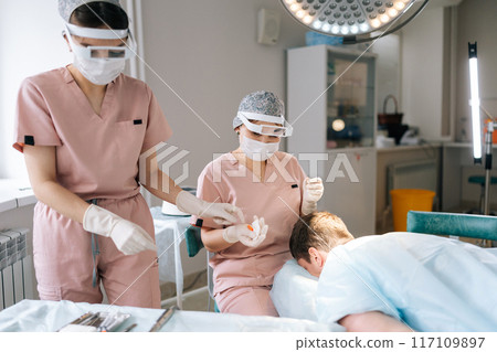 Unrecognizable patient receiving hair loss treatment injections in scalp by trichologist . Female dermatologist performing local anesthesia to back of head in recipient area prior to hair transplant. 117109897