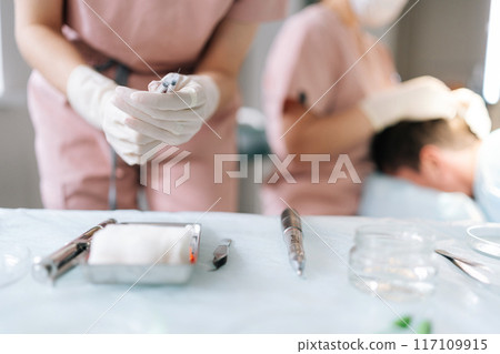 Closeup gloved hands of unrecognizable nurse assistant removing cap from needle of syringe, preparing to operation at hospital. Surgery doctor preparing syringe medicine for procedure in clinic Closeup gloved hands of unrecognizable nurse assistant removing cap from needle of syringe, preparing to operation at hospital. Surgery doctor preparing syringe medicine for procedure in clinic 117109915