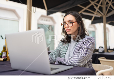 Woman working on remote from outdoor cafe Woman working on remote from outdoor cafe 117110560