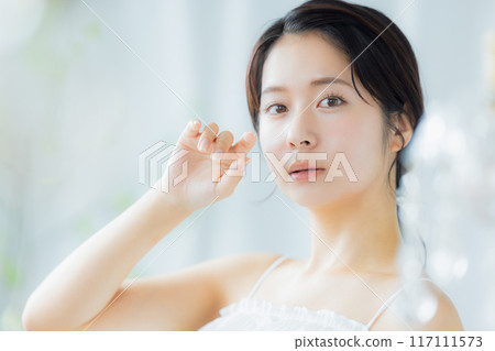 A young woman feels her skin become more moisturized 117111573