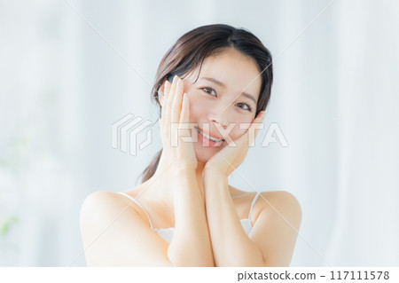 A young woman feels her skin become more moisturized 117111578