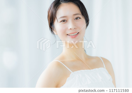 A young woman feels her skin become more moisturized 117111580