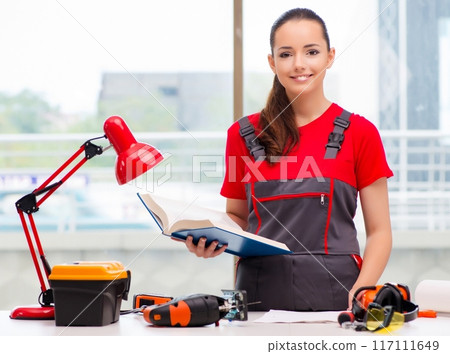 Young woman in coveralls doing repairs 117111649