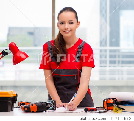 Young woman in coveralls doing repairs 117111650