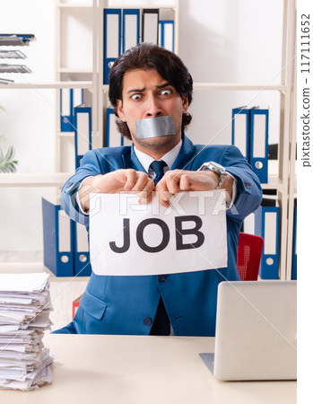 Young male employee with tape on the mouth Young male employee with tape on the mouth 117111652