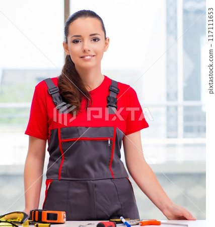 Young woman in coveralls doing repairs Young woman in coveralls doing repairs 117111653