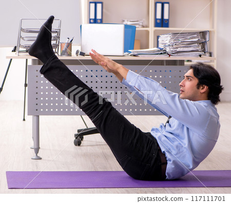 Young handsome male employee doing exercises in the office Young handsome male employee doing exercises in the office 117111701