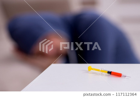 Young man having problems with narcotics at home 117112364