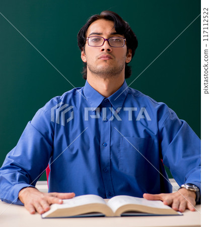 Young male teacher in front of chalkboard 117112522