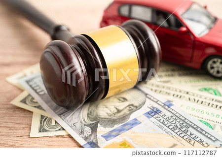 Hammer gavel judge and US dollar banknote money with car vehicle accident, insurance coverage claim lawsuit court case. 117112787