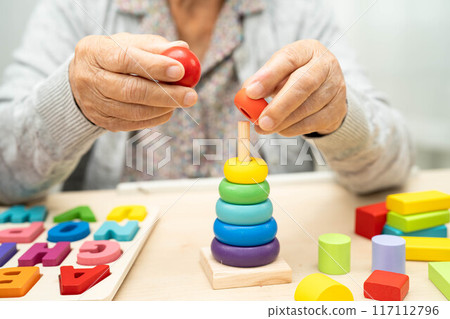 Alzheimer disease AD, Asian senior woman patient suffering from dementia learn practical motor skills rehabilitation. Alzheimer disease AD, Asian senior woman patient suffering from dementia learn practical motor skills rehabilitation. 117112796