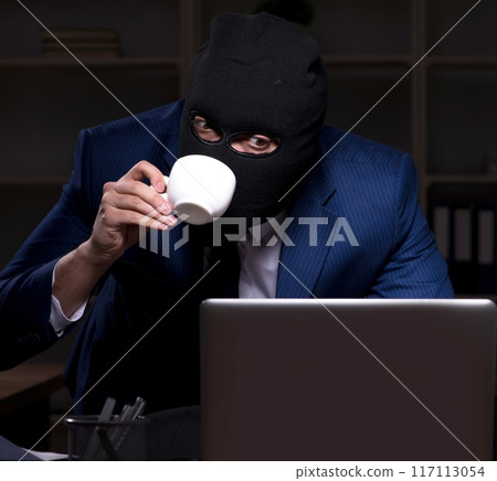Male employee stealing information in the office night time 117113054