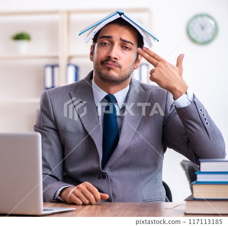 Young male businessman reading books at workplace 117113185