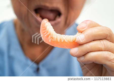 Asian elderly woman patient holding to use denture, healthy strong medical concept. 117113661