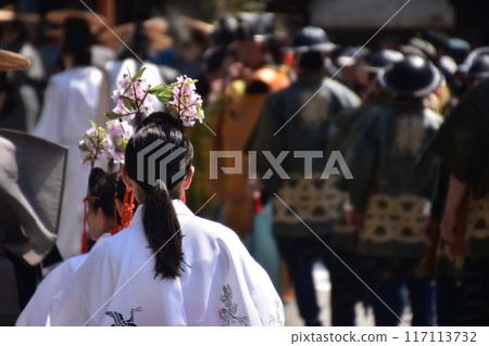 Takayama Festival in Spring, Takayama City, Gifu Prefecture, Japan. Girls participating in the Daimyo Procession, wearing white robes and flower ornaments on their heads. 117113732