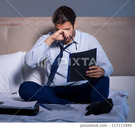 Tired businessman working overtime at home at night Tired businessman working overtime at home at night 117113990