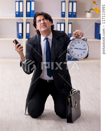 Young male employee in the office in time management concept 117113991