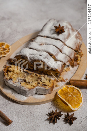 Slices of Traditional German Christmas stollen cake in background of handmade festive decor. Winter holiday treats. Vegan baking recipe 117114427