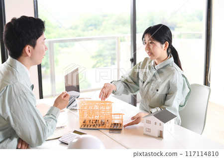 Men and women in work clothes holding a meeting using a construction model 117114810